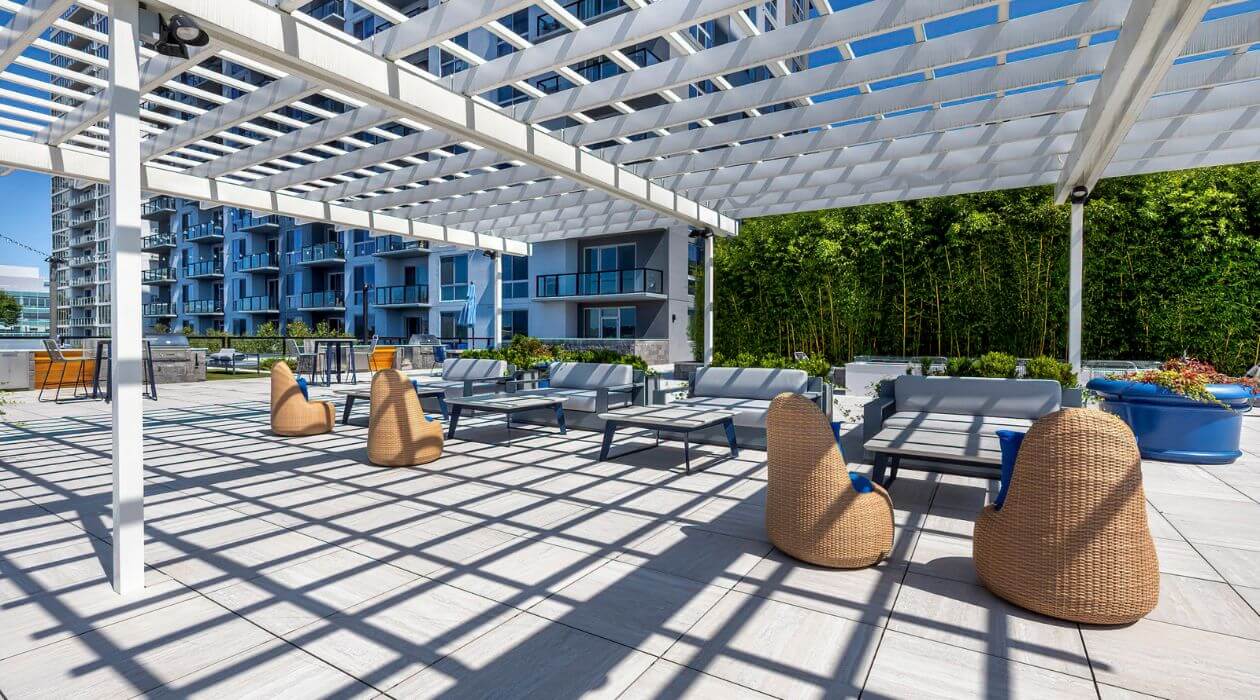 Outdoor lounge with modern seating under a white pergola at Escape at Harbor Point, Stamford, hosted by Compass Furnished Apartments.