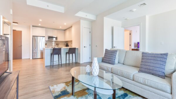 Spacious, open-concept living room and kitchen at The Alyx at EchelonSeaport, fully furnished by Compass Furnished Apartments.