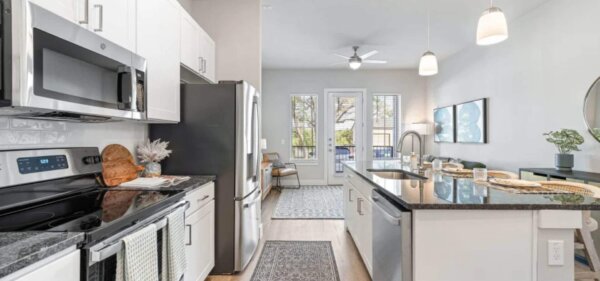 Modern kitchen at The Avery by Compass Furnished Apartments, featuring stainless steel appliances, granite countertops, and an open layout with bar seating.