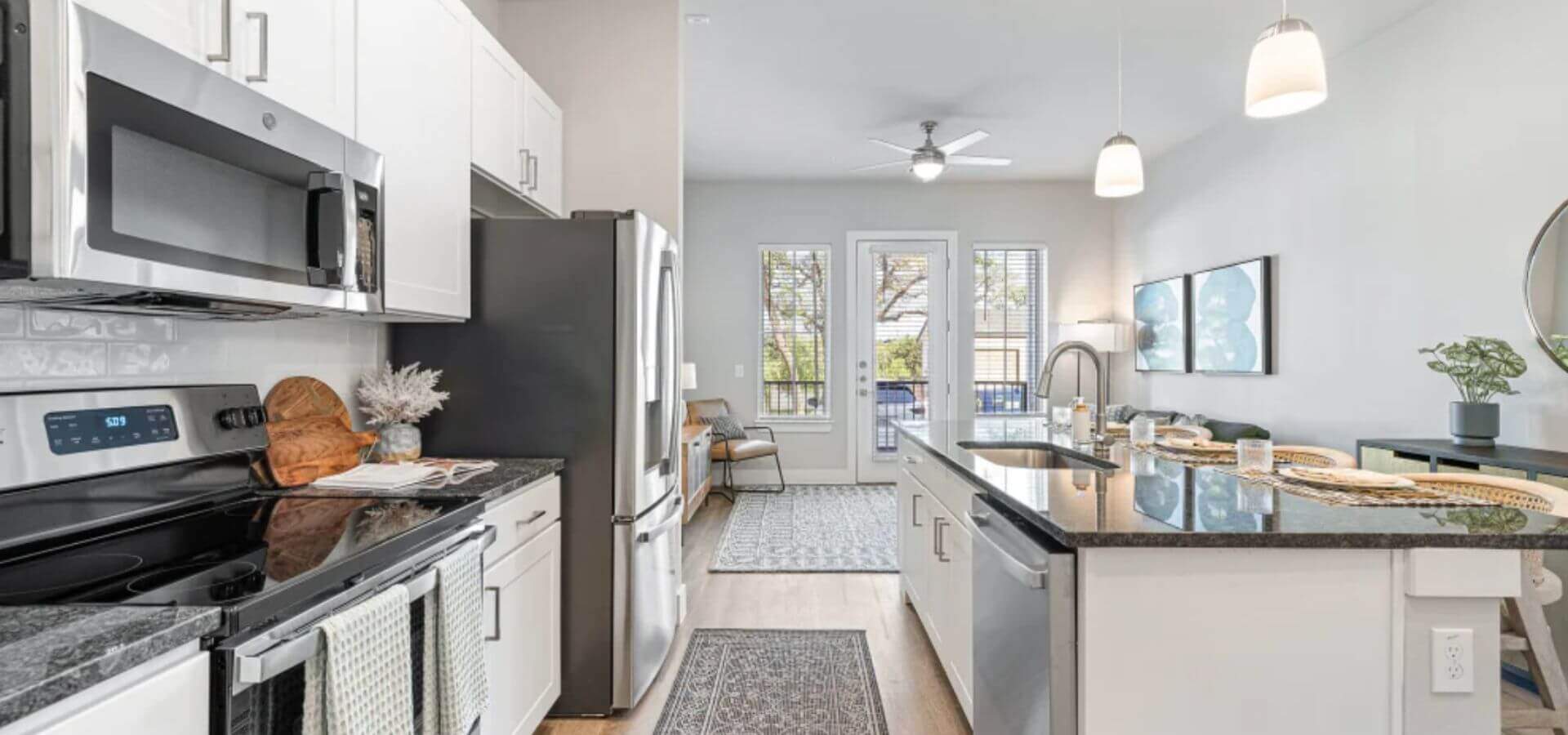 Modern kitchen at The Avery by Compass Furnished Apartments, featuring stainless steel appliances, granite countertops, and an open layout with bar seating.