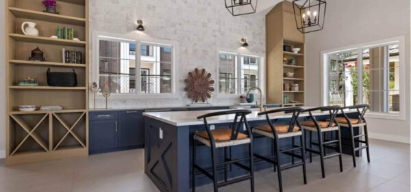 Modern kitchen space at The Avery by Compass Furnished Apartments, featuring a large island with bar seating, open shelving, and natural light through multiple windows.