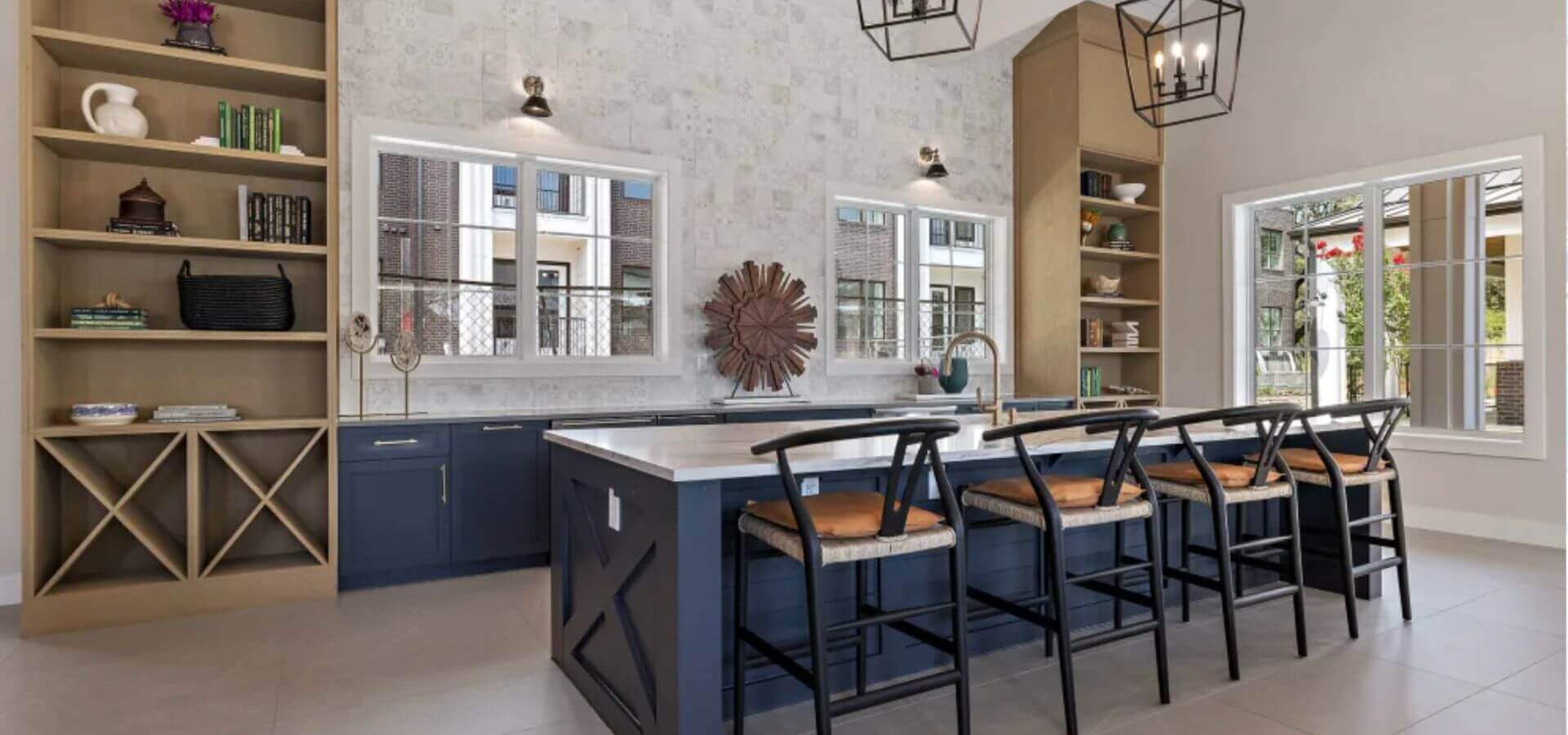 Modern kitchen space at The Avery by Compass Furnished Apartments, featuring a large island with bar seating, open shelving, and natural light through multiple windows.