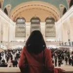 a woman stands in a train station after corporate relocation