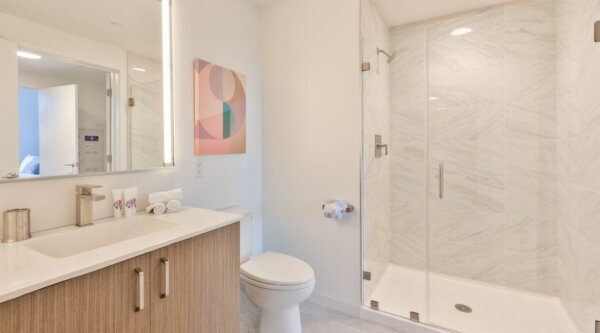 Modern bathroom with walk-in glass shower, sleek wood vanity, and minimalist decor at Compass Furnished Apartments in Idyl Fenway—designed for comfort and convenience.
