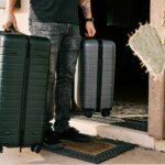 a businessman holds suitcases outside of a temporary housing