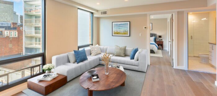 Spacious furnished apartment living room with floor-to-ceiling windows, sectional sofa, and view of downtown Boston at 244 Hanover.