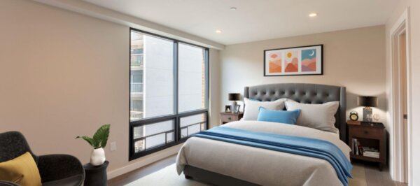 Bright and modern bedroom at 244 Hanover with a tufted headboard, soft linens, and floor-to-ceiling windows.