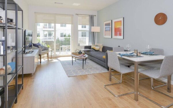 A bright and modern furnished apartment at 75 Tresser, featuring a stylish living and dining area with balcony access—available through Compass Furnished Apartments.