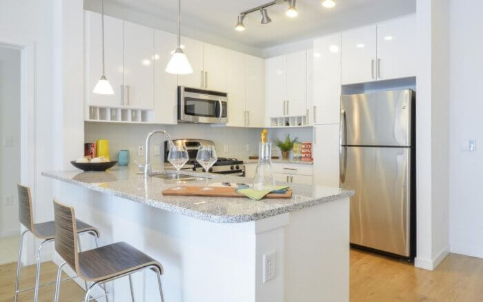 Bright modern kitchen with granite countertops, stainless steel appliances, and white cabinetry at 75 Tresser by Compass Furnished Apartments.
