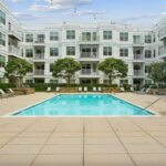 Sparkling outdoor swimming pool surrounded by lounge chairs at 75 Tresser by Compass Furnished Apartments.