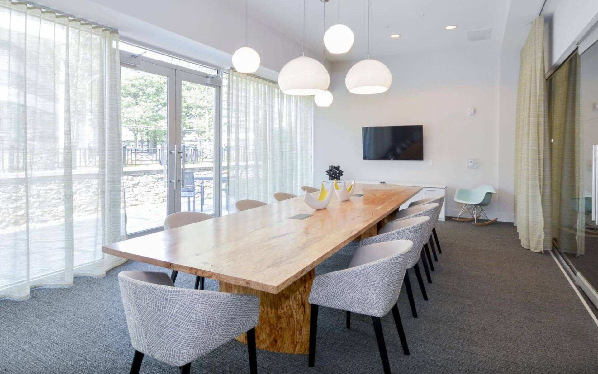 Bright and modern conference room with large wooden table at 75 Tresser by Compass Furnished Apartments.