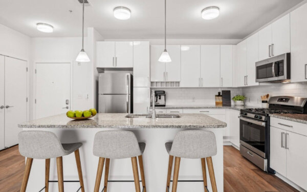 Contemporary kitchen with large island, stainless steel appliances, and modern pendant lighting at 75 Tresser by Compass Furnished Apartments.