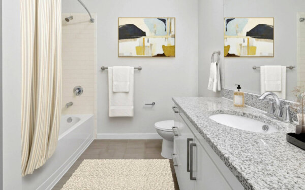 Contemporary bathroom with granite countertops, white cabinetry, and modern decor at 75 Tresser by Compass Furnished Apartments.