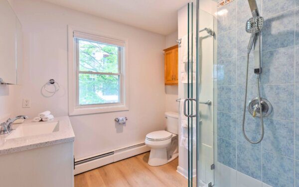 Bright bathroom with glass-enclosed shower, modern fixtures, and natural light at Compass Furnished Apartments, 235 Cardinal Medeiros.
