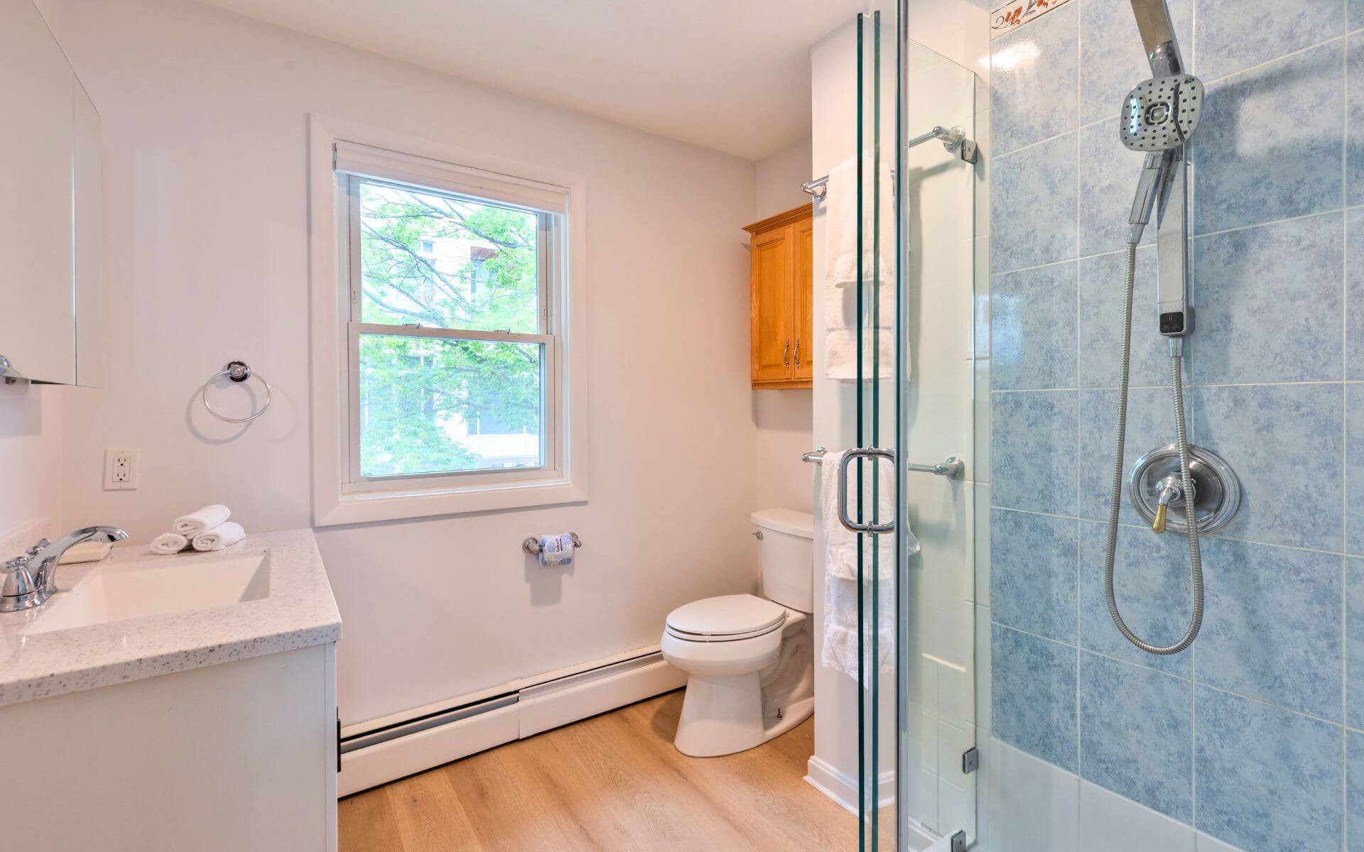 Bright bathroom with glass-enclosed shower, modern fixtures, and natural light at Compass Furnished Apartments, 235 Cardinal Medeiros.