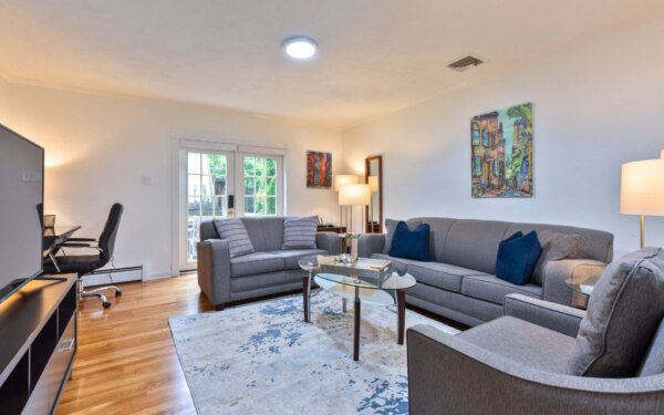 Stylish living room at 235 Cardinal Medeiros with modern grey furniture, work desk, French doors to patio, and contemporary artwork.