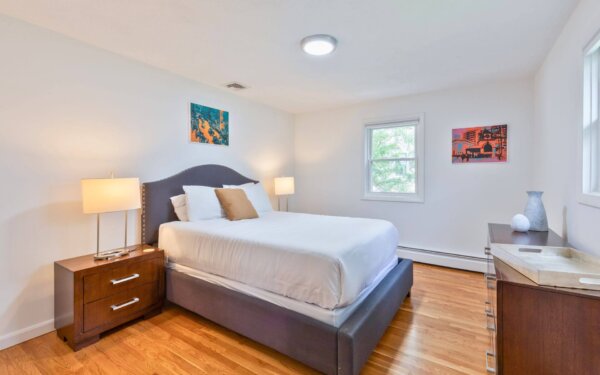 Queen bedroom with contemporary furnishings, hardwood floors, and stylish decor at Compass Furnished Apartments, 235 Cardinal Medeiros.